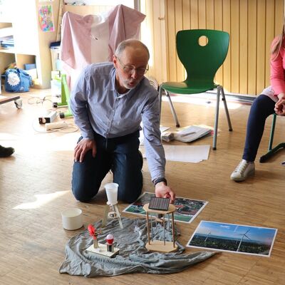 Das Bild zeigt eine Person bei dem Versuch, mit einem Solarmodul Strom zu erzeugen.