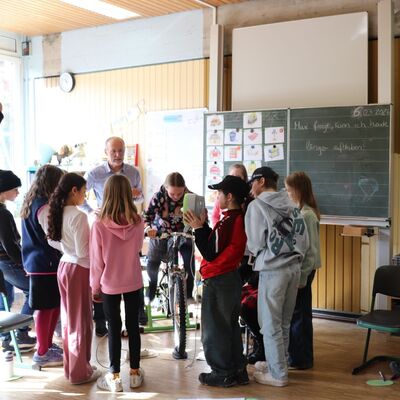 Das Bild zeigt Sch�lerinnen und Sch�ler, die mit dem Energie-Fahrrad aus eigener Muskelkraft Strom f�r einen Ventilator erzeugen.