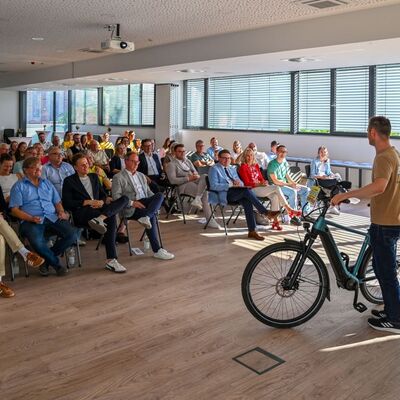 Das Bild zeigt Marvin Esser, Gesch�ftsf�hrer der Firma 2-Rad Esser GmbH & Co. KG, gemeinsam mit den Teilnehmenden bei der Pr�mierungsveranstaltung der Aktion Stadtradeln im gro�en Sitzungssaal des Landratsamtes Main-Tauber-Kreis. Er erkl�rt in seinem Vortrag unter anderem die richtigen ergonomischen Einstellungen am Fahrrad.